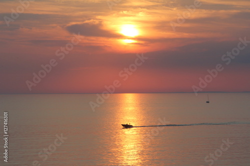 silhouettes of boats  yachts  ship on the background of sunset  sunrise  yellow  orange sky at sea