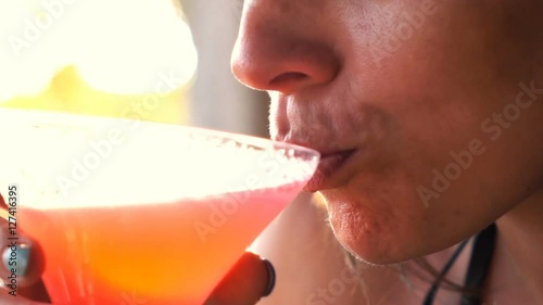 Woman drinking exotic cocktail sitting in bar, super slow motion 240fps

