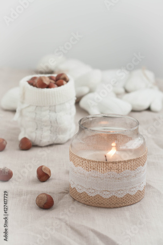 A candle  nuts in a knitted sleve. Burlap background. 