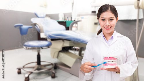 dentist showing toothbrush and dental model in dental clinic