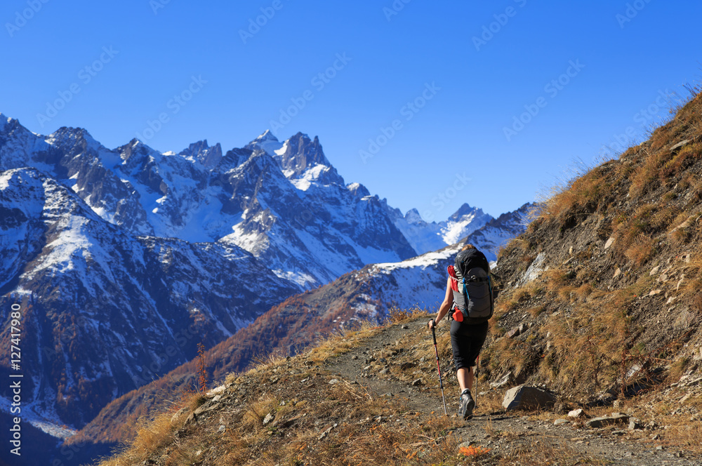 Female hiker on a trail in the French Ercins mountains on an autumn day.