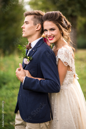 Bride and groom embracing in the park, look at camera, portrait