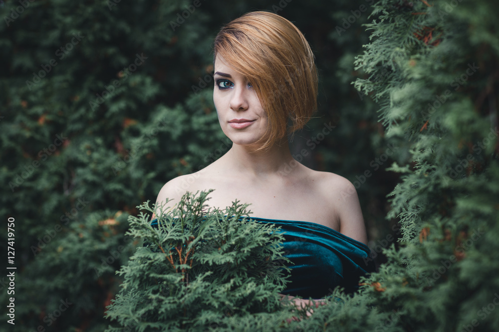 Beautiful girl standing among the trees. She smiles Beautiful girl standing among the trees. She smiles