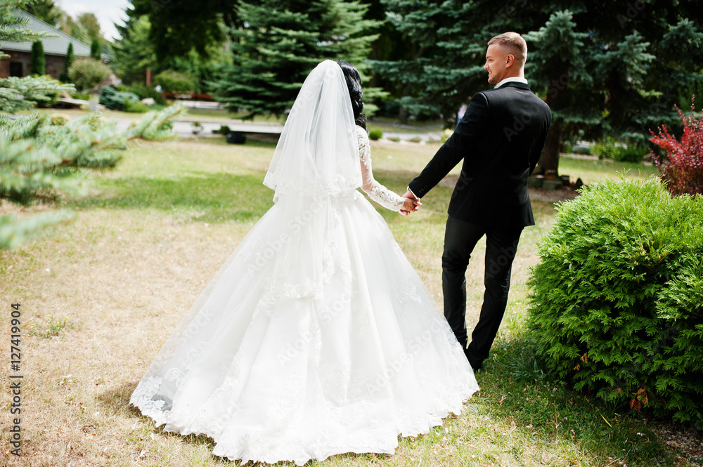 Back view of walking wedding couple at garden of courtyard.