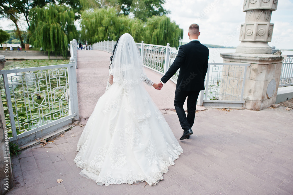 Back view of walking wedding couple at bridge to island of love. Back view of walking wedding couple at bridge to island of love.