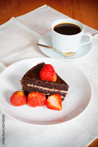 Chocolate cake with fresh strawberry and a cup of coffee. Selective focus on cake
