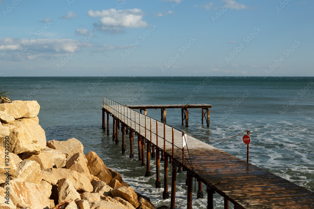 Closed old bridge over the sea with stop sign Closed old bridge over the sea with stop sign