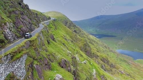 The view of the cliff and the Skyroad in the mountain with a black car passing on the long road  in Ireland
