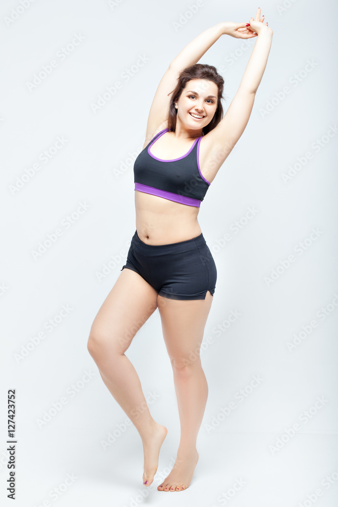 Portrait of beautiful smiling plump woman in a sports underwear on a white background
