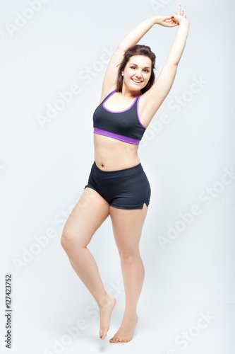 Portrait of beautiful smiling plump woman in a sports underwear on a white background © silkstocking