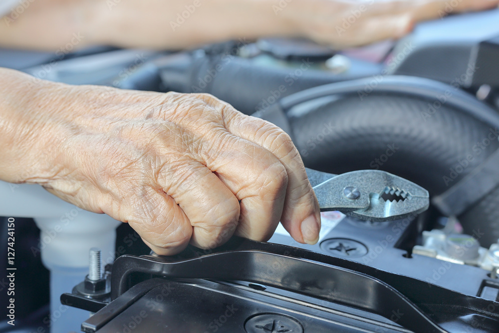 Elderly woman repairing her car