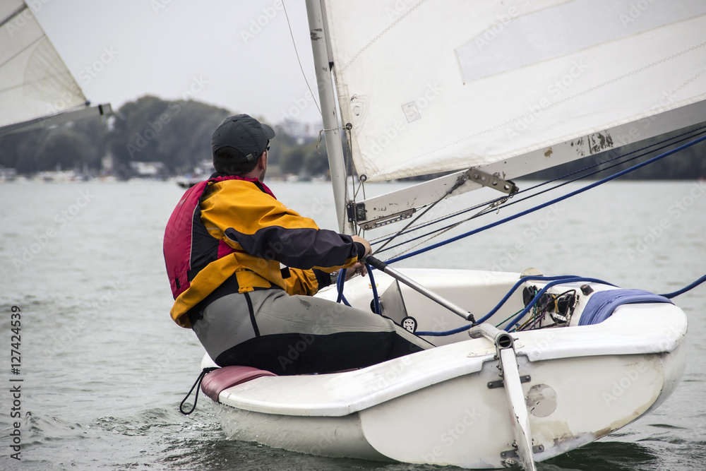 Obraz premium Man in the Finn-Class sailboat participates in one of the match race regattas on the Sava river, Belgrade, Serbia