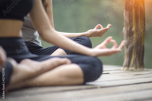 Woman yoga finger acting on hands in soft focus foreground with Nature surrounding