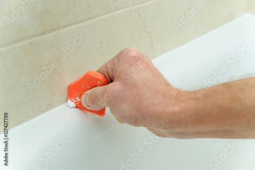 Photography Worker smoothing silicone sealant.
