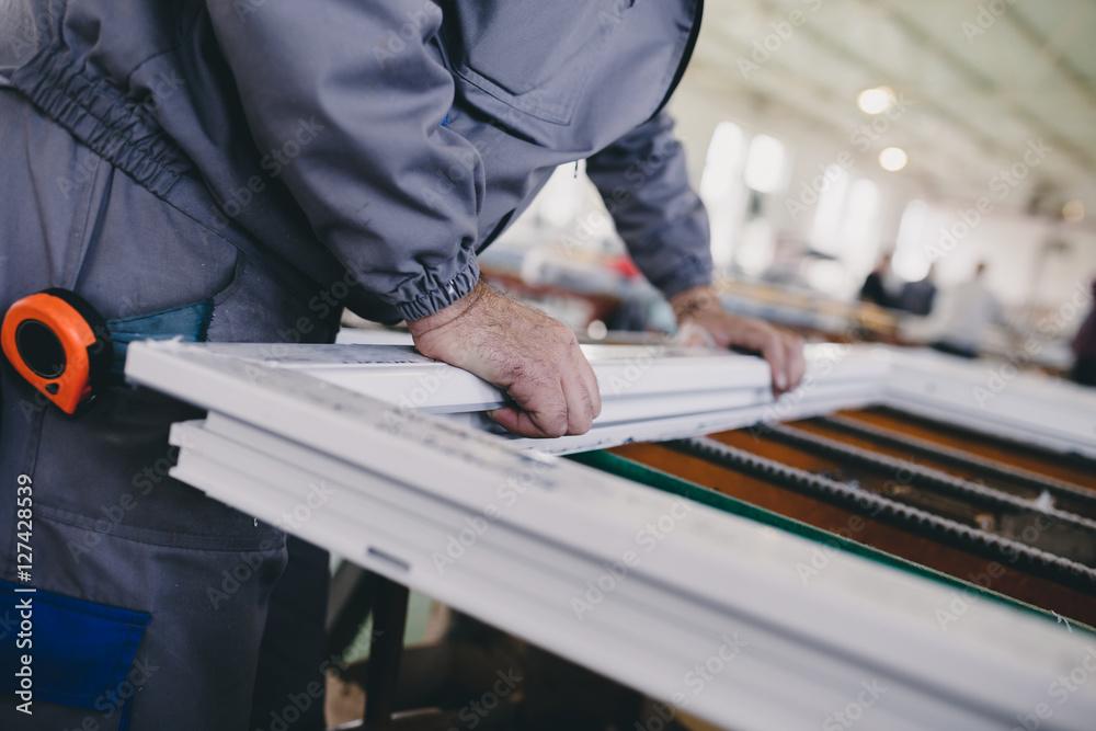 Manual worker assembling PVC doors and windows. Manufacturing jobs. Selective focus. Factory for aluminum and PVC windows and doors production. Manual worker assembling PVC doors and windows. Manufacturing jobs. Selective focus. Factory for aluminum and PVC windows and doors production.