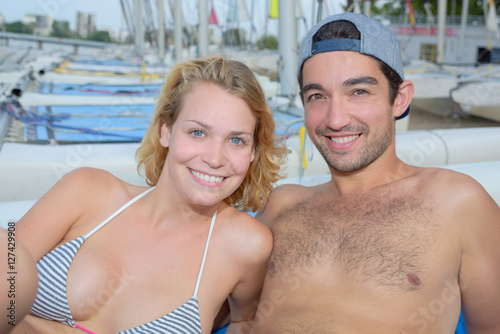 Slika na platnu cheerful couple laying next to sailboats