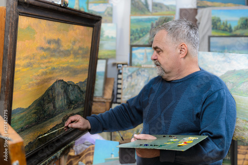 artist paints oil painting with a brush and palette photo