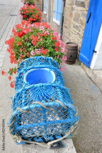 Casier de pêche bleu servant de décoration devant une maison de style breton