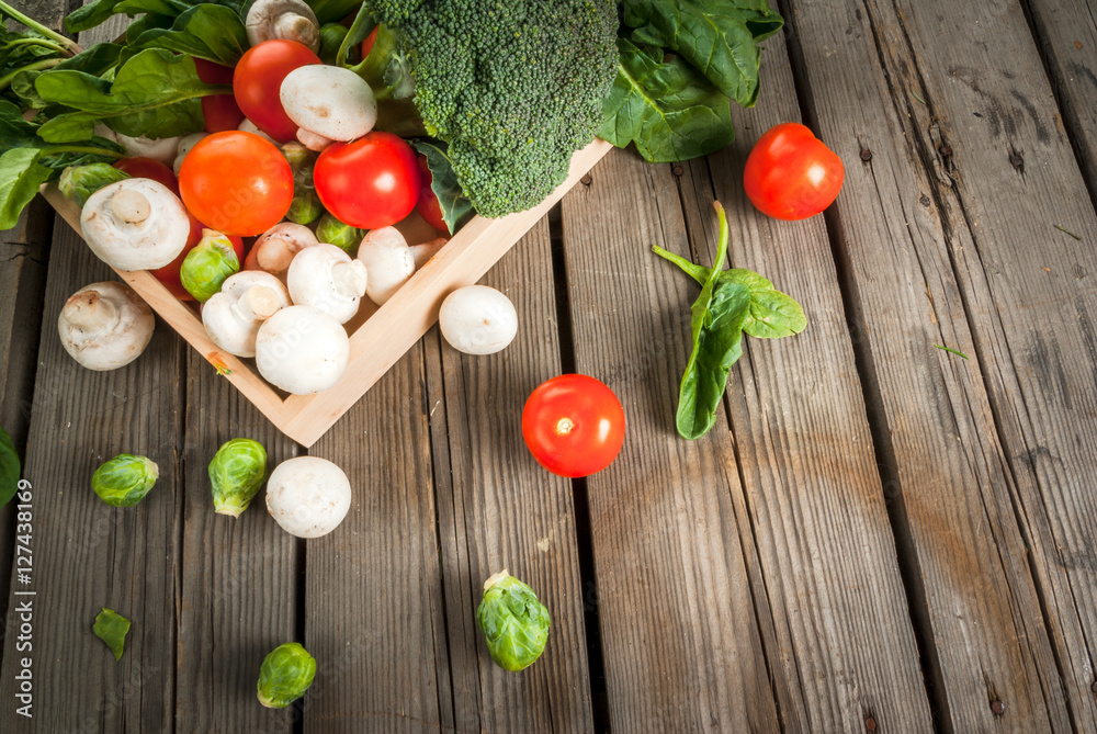 Fresh raw organic vegetables on a rustic wooden table in basket: spinach, broccoli, Brussels sprouts, tomatoes, mushrooms, champignons. Copy space Fresh raw organic vegetables on a rustic wooden table in basket: spinach, broccoli, Brussels sprouts, tomatoes, mushrooms, champignons. Copy space