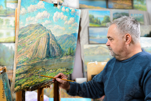 artist paints oil painting with a brush and palette photo