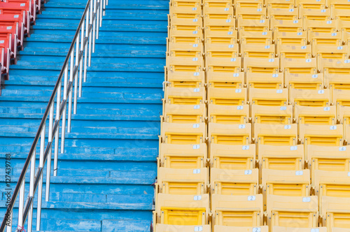 Empty orange and yellow seats at stadium Rows of seat on a soccer stadium