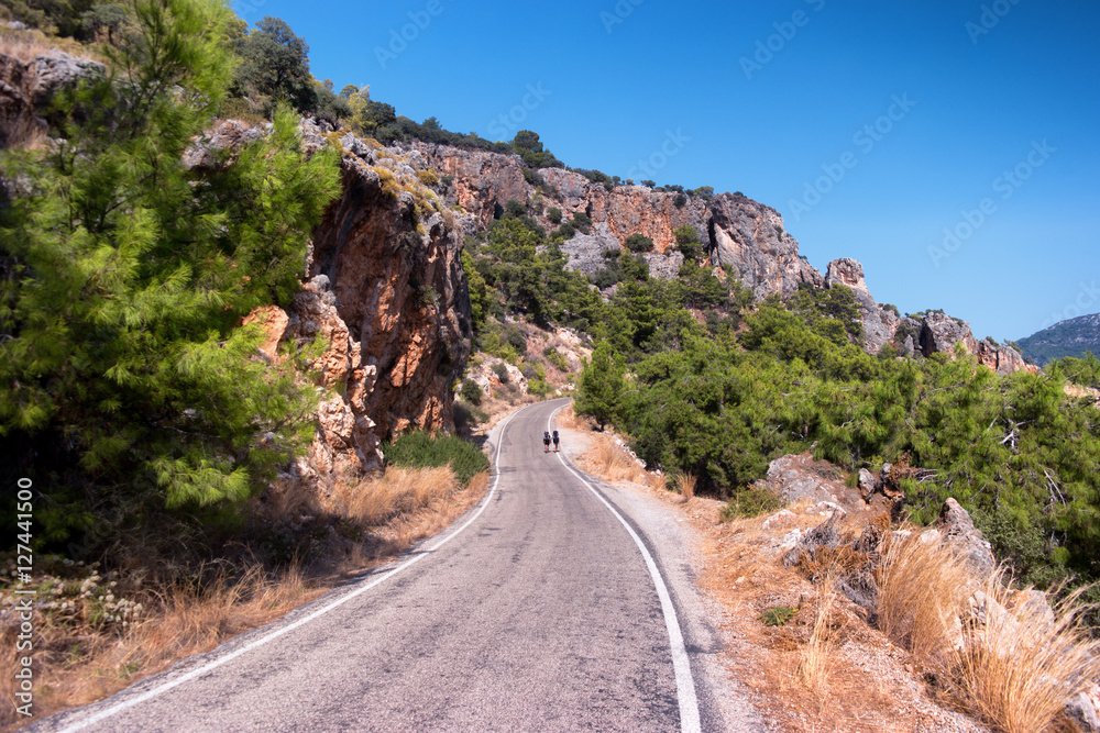 Two Young Tourist Hikes With Backpacks Going by the Road in the Two Young Tourist Hikes With Backpacks Going by the Road in the