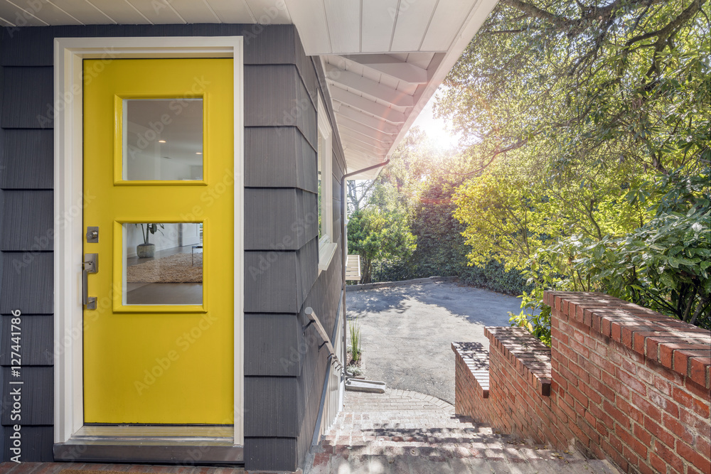 Naklejka premium Modern yellow front door with stainless steel handle and glass.
