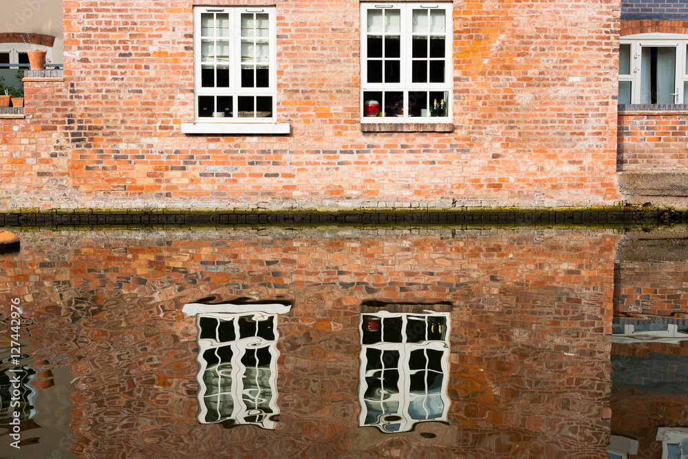 Abstract water reflections of old red brick buildings with windows in canal on a sunny day in England UK Abstract water reflections of old red brick buildings with windows in canal on a sunny day in England UK