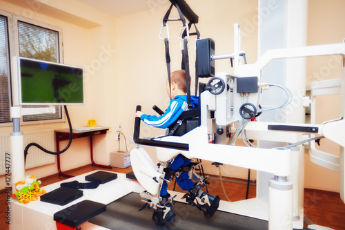 Fotografija young boy passes robotic gait therapy in rehabilitation center