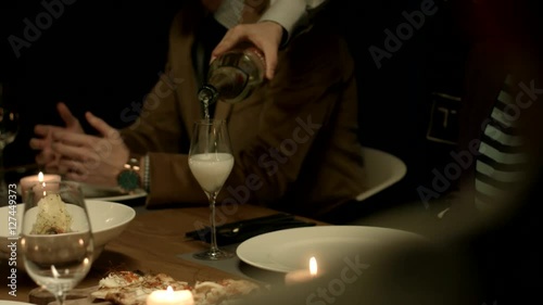 Waiter pours wine to a guest at a restaurant. 
