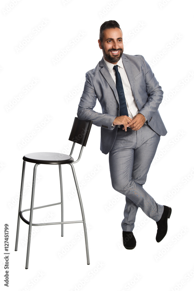 Attractive businessman in a grey suit, white shirt and blue tie with a chair. White background. Attractive businessman in a grey suit, white shirt and blue tie with a chair. White background.