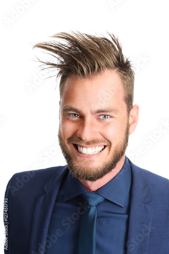 Crazy looking businessman in a blue suit and tie, smiling towards camera. White background.