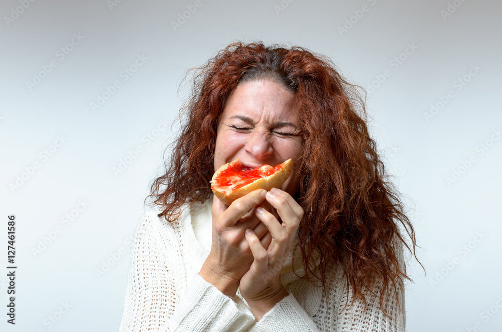 Young woman biting into a jam sandwich Young woman biting into a jam sandwich