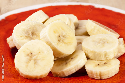 Slices of fruit of banana on red plate , close up