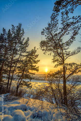 Obraz na płótnie Landscape with sunset on frozen river and forest w salonie