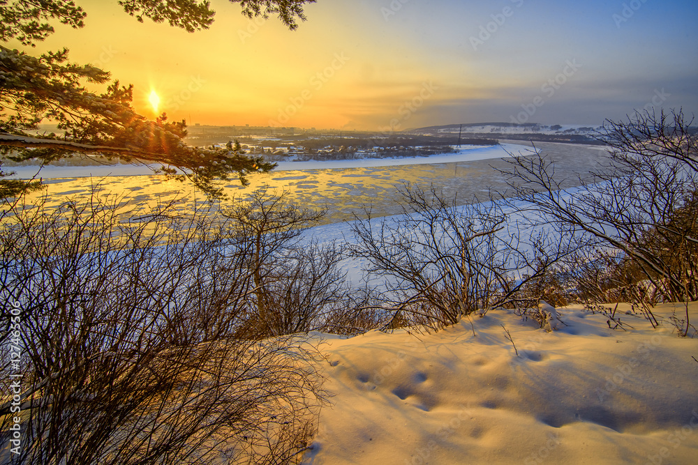 Beautiful frosty sunset on frozen river watching from winter for