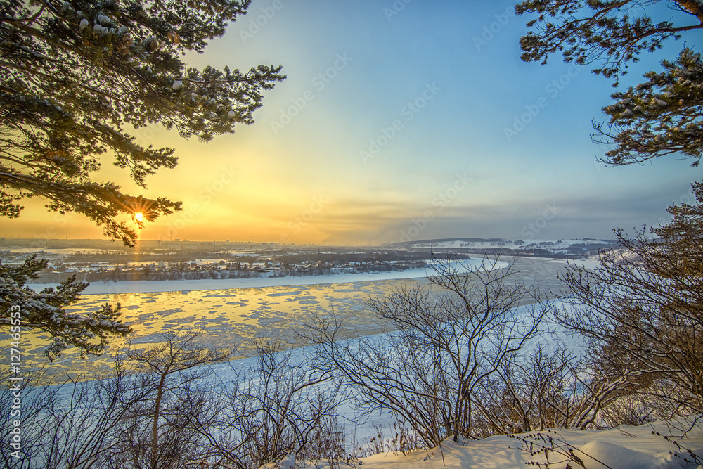 Beautiful frosty sunset on frozen river watching from winter for