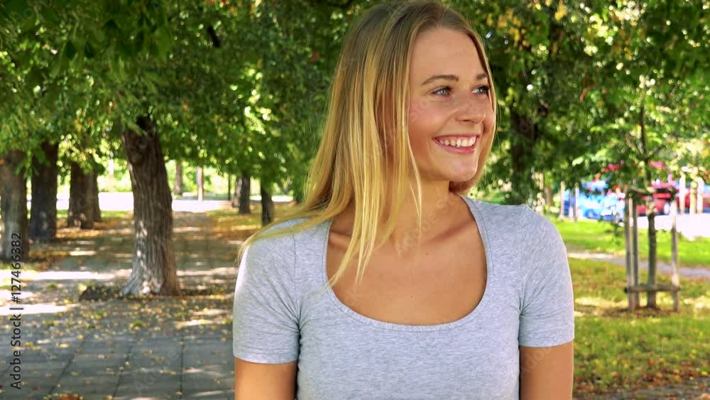 young pretty blond woman rejoices - park with trees in background young pretty blond woman rejoices - park with trees in background