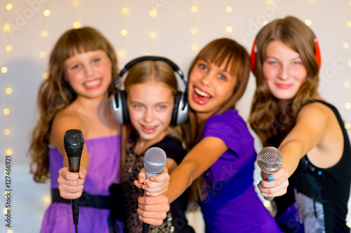 Group of happy girls singing on karaoke