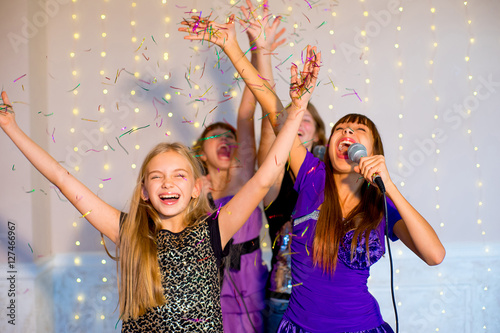 Group of happy girls singing on karaoke