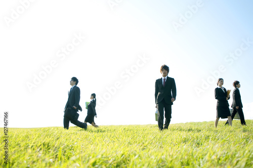 草原を歩くビジネスマンとビジネスウーマン