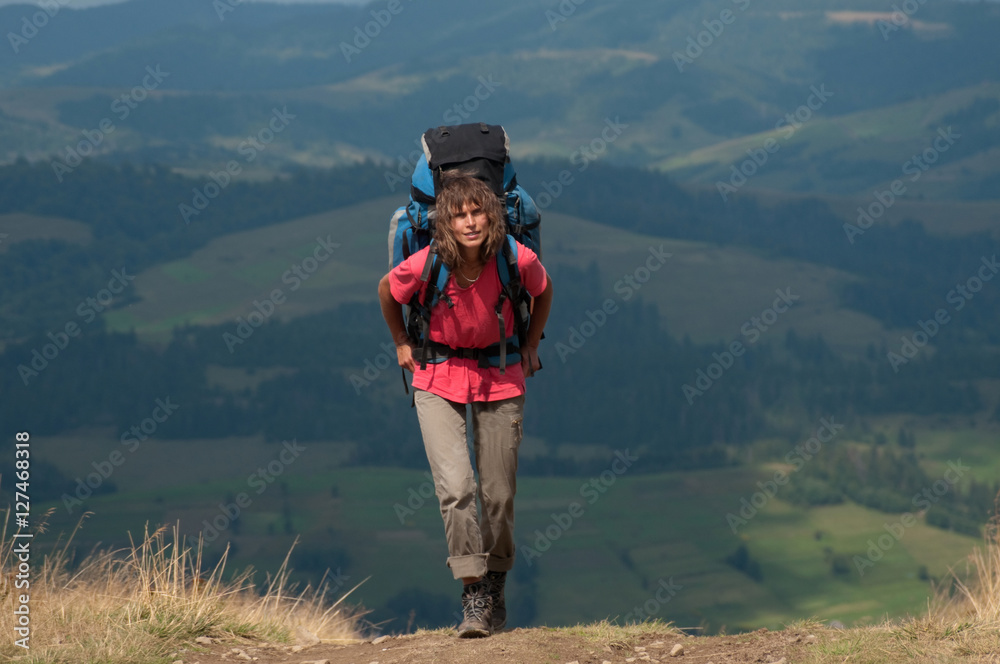 Woman with big backpack in mountains