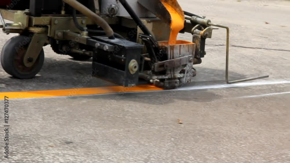 Man painting the yellow line on the concrete floor at car park