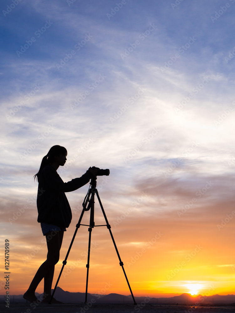 Girl photographer with camera at sunset