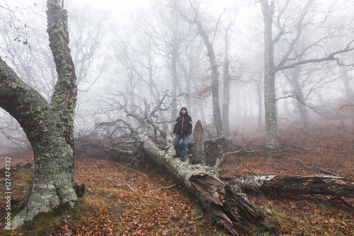 Man alone in mysterious and mystic dense forest in misty haze