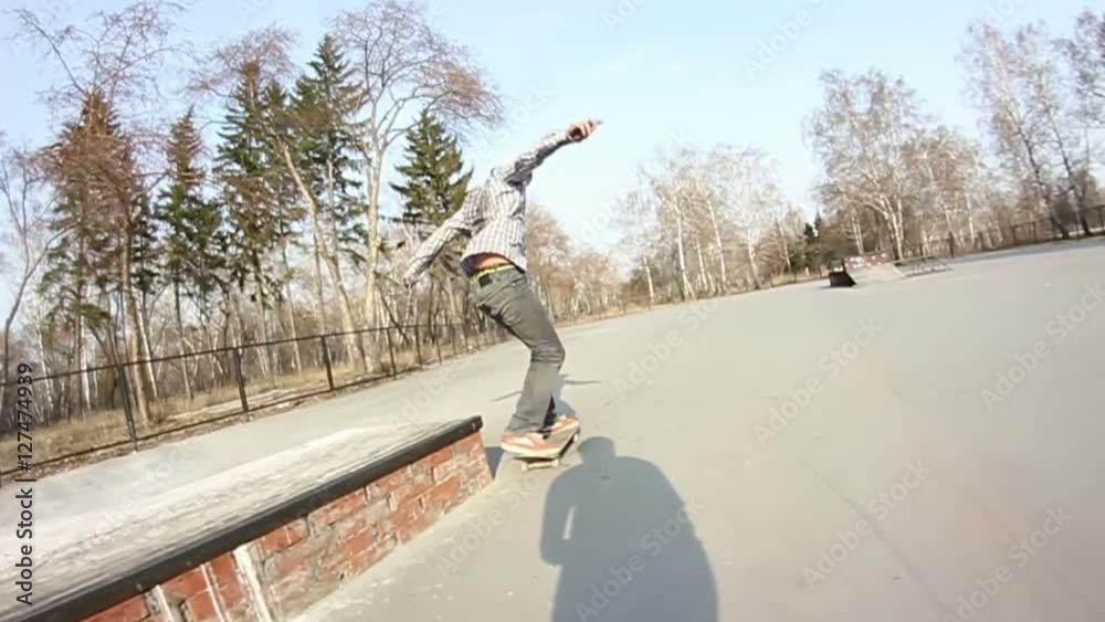 Young man doing stunts on a skateboard in line skate park.