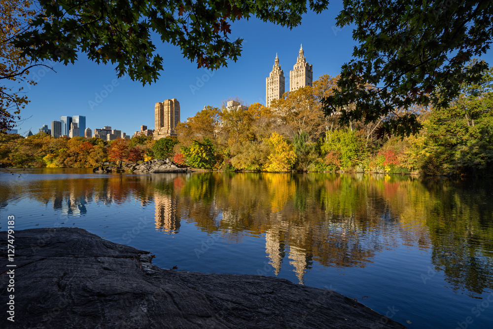 Fall in Central Park at The Lake. Cityscape sunrise view with colorful Autumn foliage on the Upper West Side. Manhattan, New York City