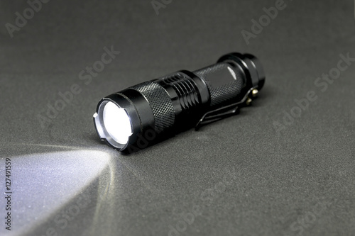 Closeup pocket LED flashlight on dark background. © ETAP