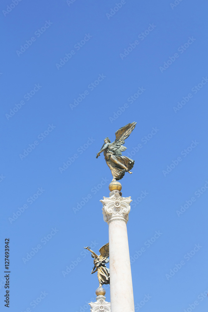 View of winged woman statues at Altar of the Fatherland in Rome. Grand marble, classical temple honoring Italy's first king & First World War soldiers. View of winged woman statues at Altar of the Fatherland in Rome. Grand marble, classical temple honoring Italy's first king & First World War soldiers.