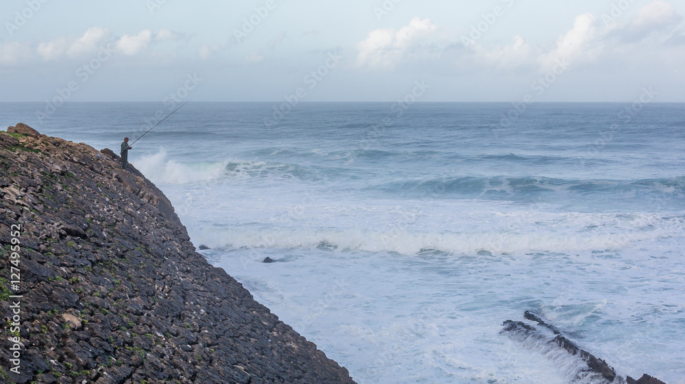Fishing in the waves of the Atlantic ocean. Praia do Guincho, Cascais, Portugal. Fishing in the waves of the Atlantic ocean. Praia do Guincho, Cascais, Portugal.